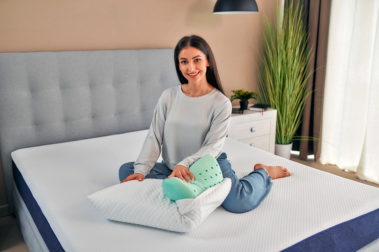 La mujer sentada en la cama con la almohada V1A